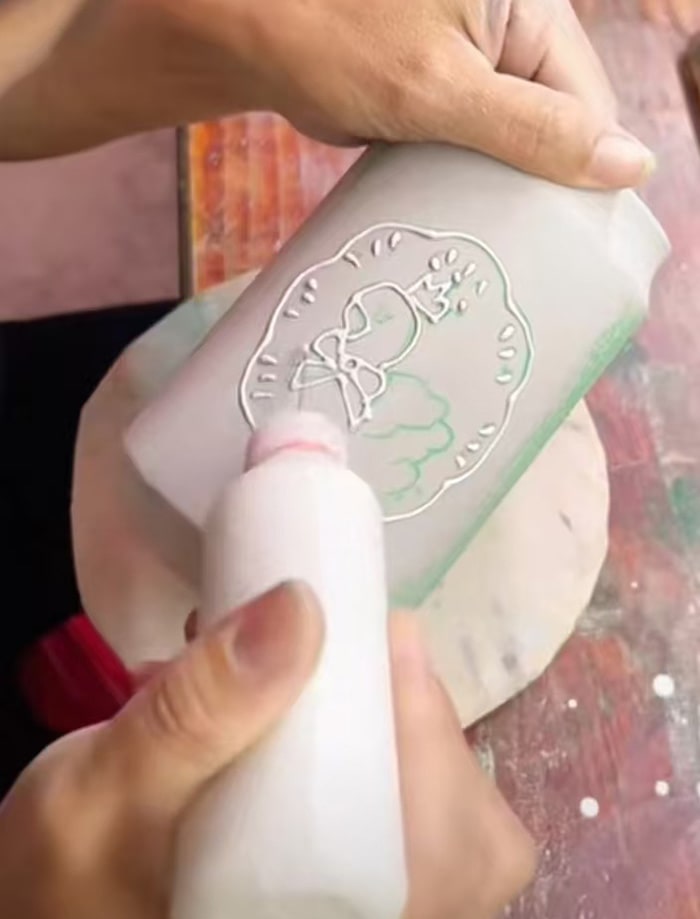 a packagin expert doing glazing embossing on a bottle
