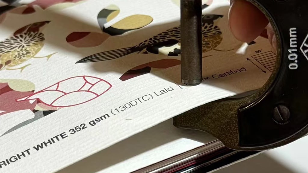 measuring the thickness of a 352gsm paper sheet to demonstrate what is GSM in paper weight