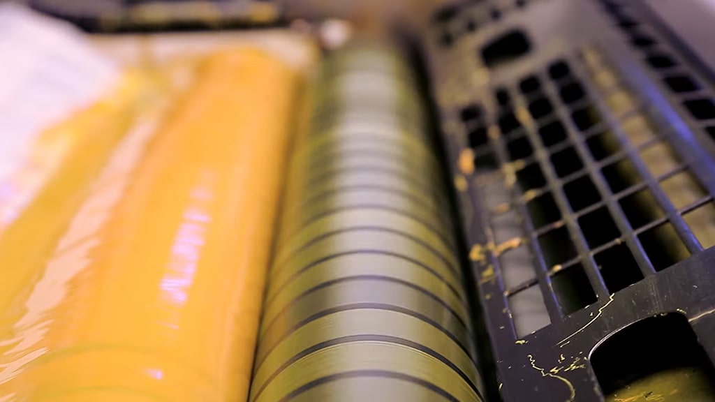 inking rollers applying CMYK ink in the offset printing process